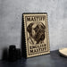 A metal sign with a stamp-like design featuring a mastiff dog, placed on a countertop next to some black camera lenses.