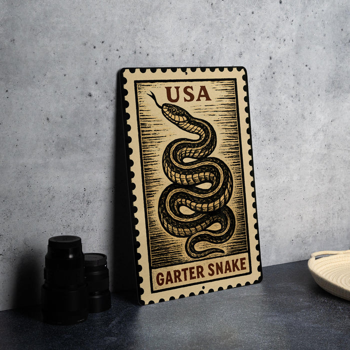 A metal sign with a snake design and the text "USA GARTER Snake" is displayed on a table.