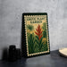 a poster or sign with a tropical plant design, placed on a table next to some black containers.