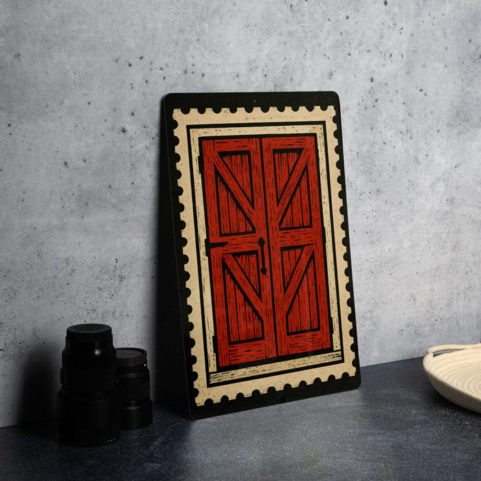 a red wooden door with a black border, set against a gray wall.