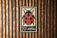 A metal sign featuring a ladybug illustration is mounted on a wooden wall.
