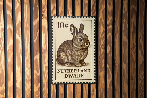 A 10 cent postage stamp from the Netherlands, featuring a rabbit, is displayed on a wooden wall.