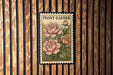 A framed image of a peony flower is displayed on a wooden wall.
