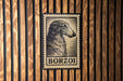 A vintage-style postage stamp featuring a dog's head is displayed on a wooden wall.