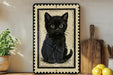 a framed illustration of a black cat sitting on a surface, surrounded by various kitchen items such as a wooden cutting board, a lemon, and a potted plant.
