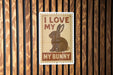 A sign with the text "I LOVE MY BUNNY" and an illustration of a rabbit is displayed on a wooden wall.