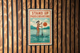A vintage-style sign with the text "STAND UP PADDLEBOARDING" and an illustration of a woman paddleboarding on a lake.