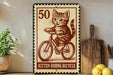 A vintage-style metal sign depicting a kitten riding a bicycle, with the number 50 and the text "Kitten Riding Bicycle" printed on it.
