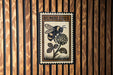 A metal stamp with a bumblebee illustration on it, mounted on a wooden wall.