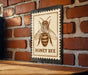 A wooden table with a metal honey bee stamp on it, mounted on a brick wall.