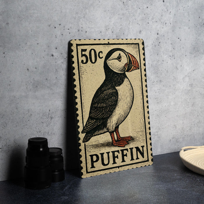 A 50 cent postage stamp featuring a puffin bird, placed on a dark surface next to some black camera lenses.