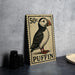 A 50 cent postage stamp featuring a puffin bird, placed on a dark surface next to some black camera lenses.