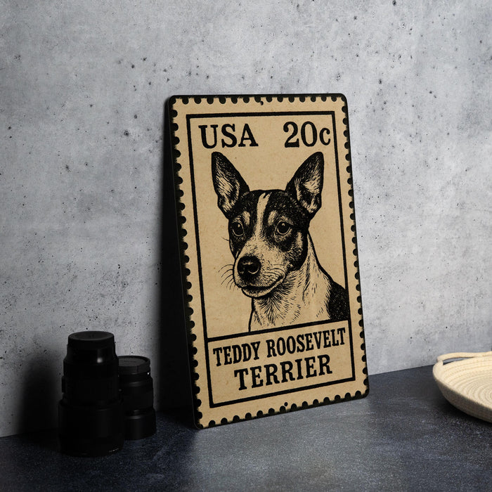 A framed postage stamp featuring a portrait of Teddy Roosevelt Terrier, a small black and white dog.