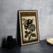 A framed illustration of a bumblebee on a flower is displayed on a table, accompanied by a stack of black camera lenses and a woven basket.