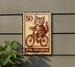 A sign featuring a cat riding a bicycle, with the number 50 and the text "Kitten Riding Bicycle" displayed on it.
