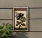 a decorative sign with a bee and a flower, mounted on a wall.