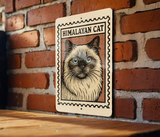 A framed image of a Himalayan cat is displayed on a brick wall.