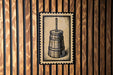 A wooden wall with a metal stamp featuring a wooden barrel with a spout on it.