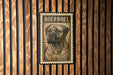 A metal sign with a printed image of a Boerboel dog on it, mounted on a wooden wall.
