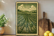 a framed illustration of a countryside landscape with a field of trees and rolling hills, accompanied by a wooden cutting board and a potted plant on a shelf.