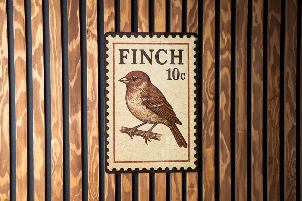 A postage stamp-like sign with a brown finch illustration and the text "FINCH 10c" is displayed on a wooden wall.