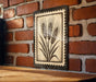 a wooden table with a framed picture of wheat hanging on the wall above it.