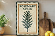 A decorative sign for "Rosesmary Sprig" is displayed on a wooden shelf, accompanied by a potted plant, a wooden cutting board, and some lemons.