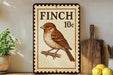 a decorative sign with a bird illustration, placed on a shelf next to a wooden cutting board and some lemons.