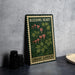 A framed poster of a bleeding heart plant with a green border and red heart-shaped flowers is displayed on a table.
