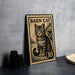 a metal sign with a cat illustration, placed on a table next to some black camera lenses.