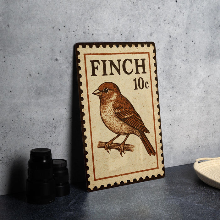 A metal sign with a bird illustration and the text "FINCH 10c" is displayed on a table.
