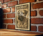 A metal sign with a printed image of a Boerboel dog is mounted on a brick wall.