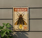 A framed image of a Firefly insect is mounted on a wall, with a plant visible to the left.