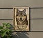 a grey wolf with a stamp-like border, mounted on a wall next to a plant.