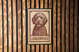 A vintage-style stamp featuring a Labradoroodle dog is displayed on a wooden wall.