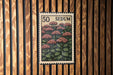 A 50 SEDUM postage stamp is displayed on a wooden wall.