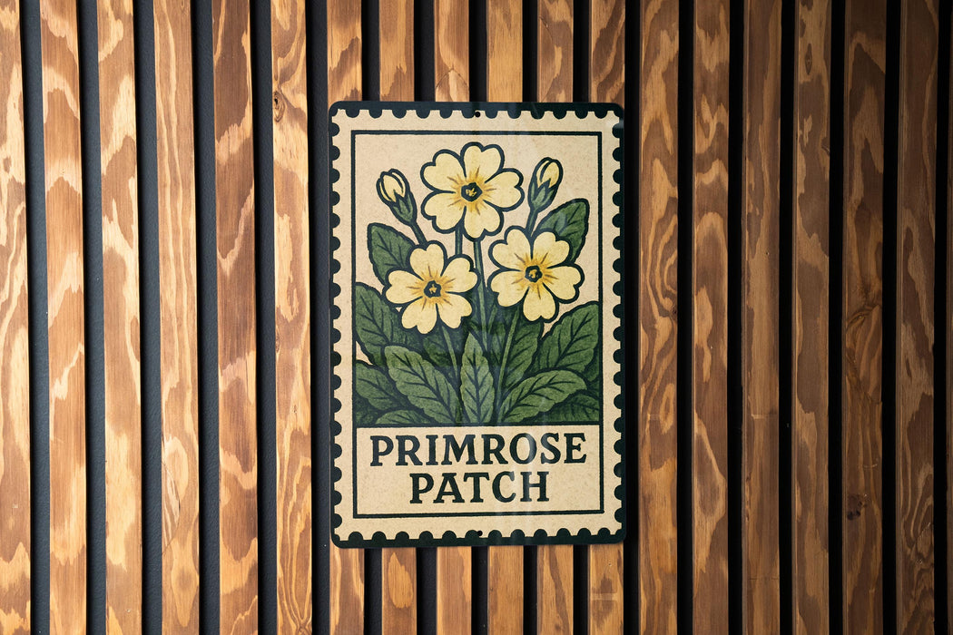 A vintage-style stamp-like sign with a floral design and the text "PRIMROSE PATCH" is displayed on a wooden wall.