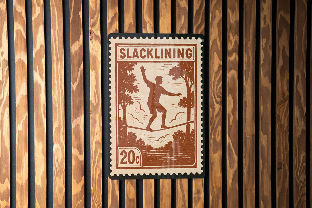 A postage stamp featuring a man walking on a tightrope, with the word "SLACKLINING" printed on it.