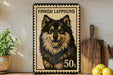 A framed image of a Finnish Lapphund dog, with the text "FINISH LAPPHUND" and "50s" printed on it, is displayed on a shelf next to a wooden cutting board and a potted plant.