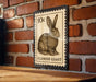 A 10c postage stamp featuring a rabbit illustration is displayed on a brick wall.