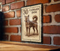 A metal stamp with a dog illustration on it, mounted on a brick wall.