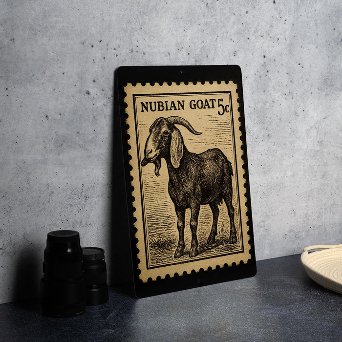 a framed stamp depicting a nubian goat, which is a type of goat. The stamp is placed on a table, and there are some black camera lenses visible in the background.
