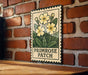 A metal sign with a floral design hangs on a brick wall, displaying the text "PRIMROSE PATCH".