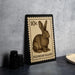 A 10c postage stamp featuring a bunny rabbit illustration, placed on a dark surface next to some black camera lenses.