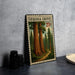A framed print of a forest scene with two towering sequoia trees is displayed on a gray wall, accompanied by a small white dish and a stack of black camera lenses.