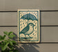 A metal sign with a bird standing under an umbrella, depicted in a woodcut style.