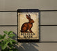 a sign with a picture of a brown hare, mounted on a wall.