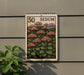 a postage stamp with a floral design, mounted on a wall next to a plant.