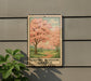 A framed image of cherry blossoms is displayed on a wall, with a plant to the left of the frame.
