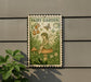 a small, vintage-style metal sign with a fairy sitting on a mushroom, surrounded by flowers and plants.